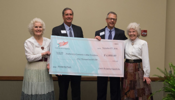 Group of people hold large check