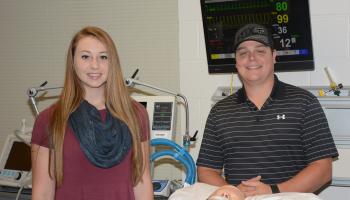 woman and man stand behind practice doll