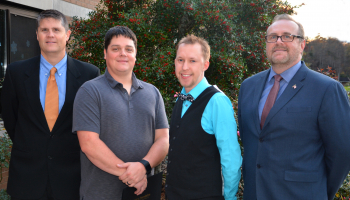 Four men stand outside a building on SCC's Jackson Campus with a tree behind them.