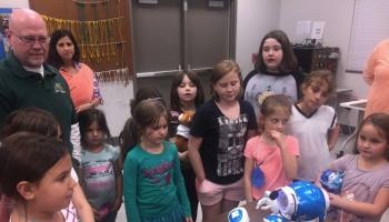 Group of people look at robot