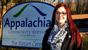 Lady stands outdoors in front of a "Balsam Center" sign