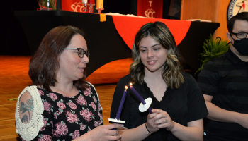 Two young ladies light candles during the ceremony.