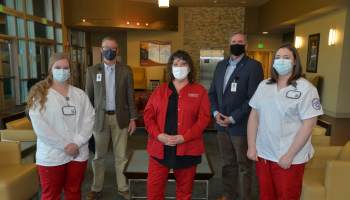 Two nursing students stand beside administrators and an instructor