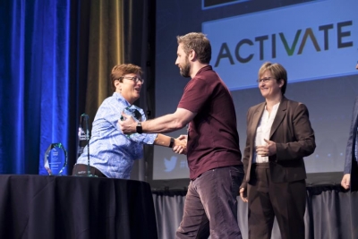 Man and woman shake hands on stage