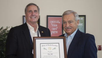 Two men hold up a plaque