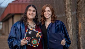 Two graduates smile outside Balsam Center on the SCC Jackson Campus