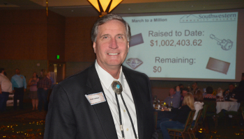 Man stands in front of a projected screen announcing that SCC's Student Success Campaign has reached $1 million.
