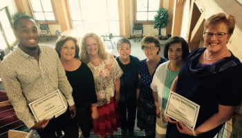 A group of six ladies and one man stand on a stairway inside a building on SCC's Macon Campus