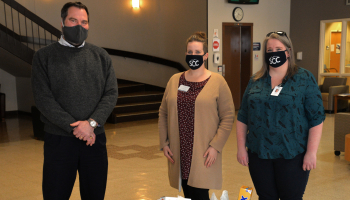 Two SCC employees present tubs filled with donations to man representing HERE.