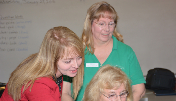 Photo of three ladies looking at a computer screen.