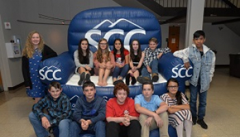 A group of young students smile while sitting on a large inflatable chair