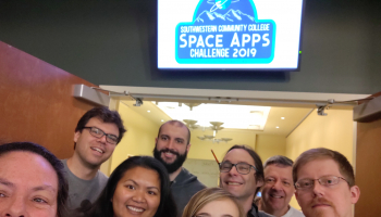 Group of mentors and young competitors stand outside a conference hall for NASA scientific competition held at SCC.