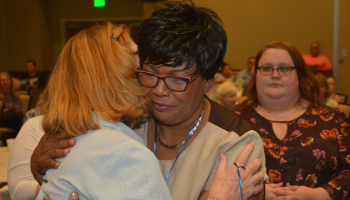 Woman hugs her instructor after receiving her pin.