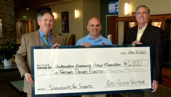 Three men hold up a large check.