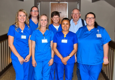 Six students wearing blue medical scrubs stand with their professor inside a building on SCC's Jackson Campus.