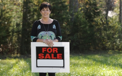 Woman holds For Sale sign