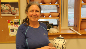 Woman holds a piece of pottery she made