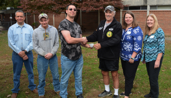 Four men and two women pose outdoors in autumn on SCC's campus in Sylva.