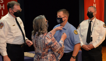 Loved one applies pin to graduate as instructors look on.