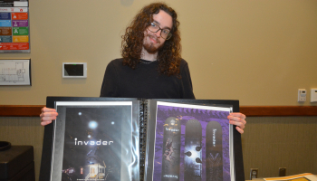 Male student holds his portfolio open to show two designs he created while attending classes at SCC.