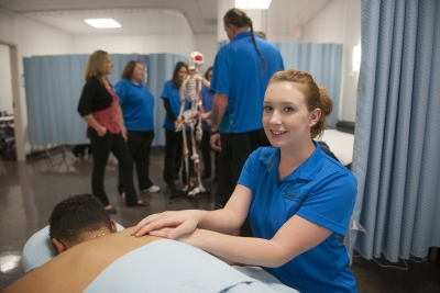 Student gives massage to man lying on table.