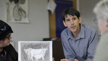 Man discusses artwork with students.