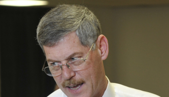 An instructor points out correct techniques for dealing a card game at a casino-like table.