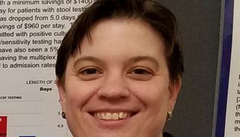 A woman smiles in front of a healthcare research poster