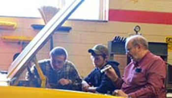Photo of Bobby Price (right) and students Ryan Younce (left) and Jesse Peavy examine an engine in Franklin High School’s automotive lab.