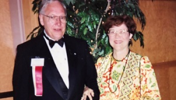 A man and woman stand together in formal dress