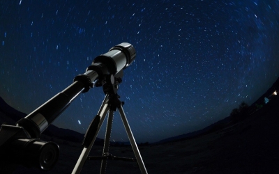 Graphic of a telescope in the foreground; stars in the background