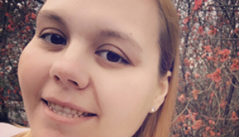 A young woman smiles for a selfie while surrounded by flowers