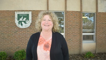 A woman smiles outside in front of a brick wall