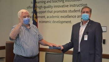 Two men place their hands on a bible