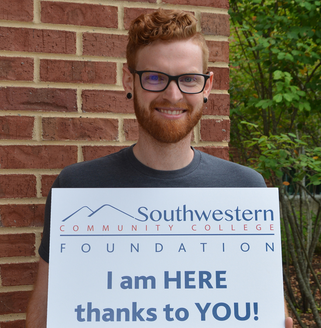 Man holds sign thanking donors for helping him go to college.