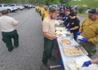 Southwestern Community College employees and area residents serve a meal to firefighters and emergency personnel on Monday, April 21, at Swain West Elementary School.