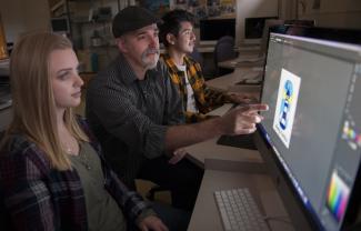 Instructor works with two students at computer monitor