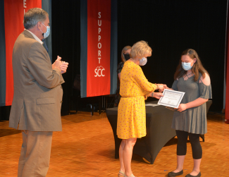 Woman hands a certificate to a student