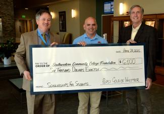 Three men hold up a large check.
