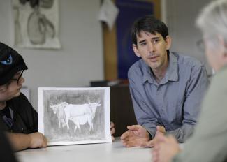 Man discusses artwork with students.